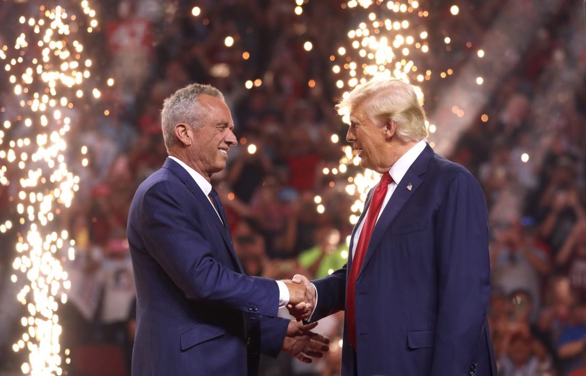 Image of Trump and R.F. Kennedy. shaking hands at rally in AZ with pyro technics in the background.