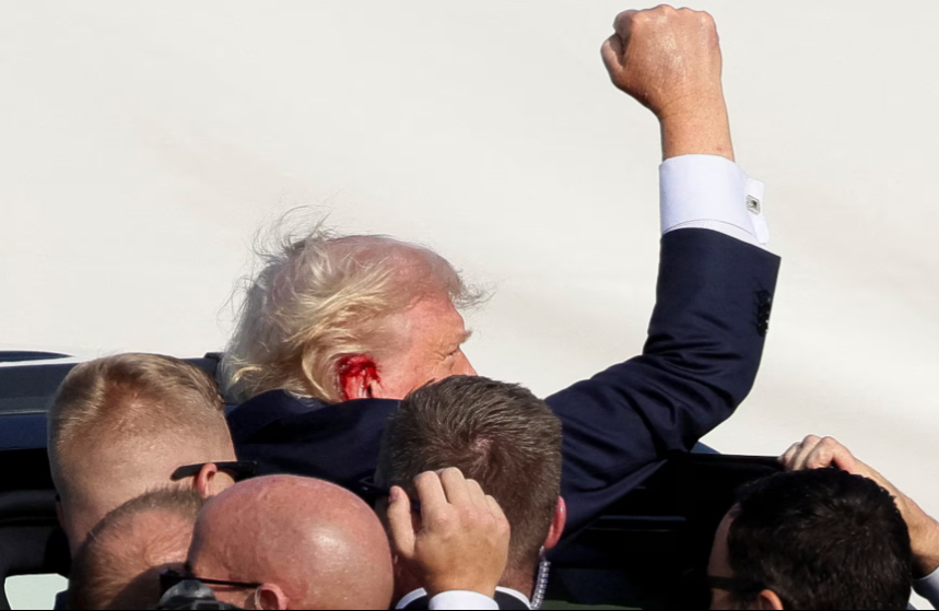 Image of Trump pumping his fist in the air with his ear bleeding.